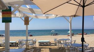 a beach with chairs and tables and umbrellas and the ocean at Apartamento a 20 metros de la playa in Calafell