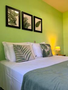 ポメロデにあるCasa ampla há 8 minutos do centroの白いベッド1台、壁に4枚の写真が飾られたベッドルーム1室