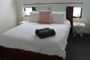 um quarto com uma cama com uma toalha preta em Peninsula Escape 100m to water em Safety Beach