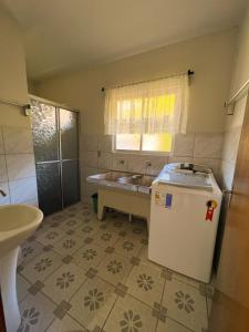 een badkamer met een bad, een wastafel en een koelkast bij Casa ampla há 8 minutos do centro in Pomerode