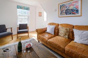 a living room with a brown couch and a bottle of wine at Frogmore Cottage in Leiston