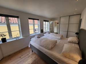 een slaapkamer met een groot bed met witte lakens en kussens bij Sunset Penthouse in Sønderborg