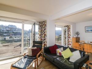 a living room with a black leather couch and a balcony at Estuary View in Plymouth