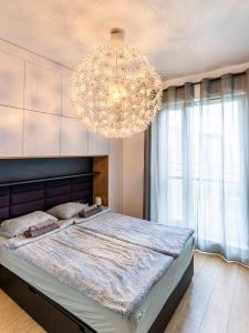 a bedroom with a large bed and a chandelier at FIRST -- Green Żoliborz Apartment 2 in Warsaw
