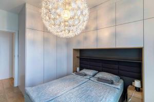 a bedroom with a large bed and a chandelier at FIRST -- Green Żoliborz Apartment 2 in Warsaw