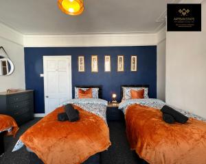 two beds in a bedroom with blue walls and orange sheets at Vintage Vibes By Artisan Stays in Southend-On-Sea I Free Parking I Long Weekend Offer in Southend-on-Sea