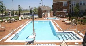 a large swimming pool with chairs and a building at Residence Inn by Marriott Wichita East At Plazzio in Wichita