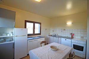 uma cozinha com uma mesa e um frigorífico branco em Les grangettes em Rilhac-Rancon