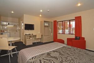 Omahu Motor Lodge في هاستينغز: غرفة نوم بسرير وطاولة ومطبخ