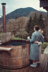 a woman standing on a wooden deck looking at a hot tub at Chalet trappeur in Le Biot