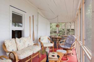 um alpendre com um sofá, cadeiras e uma mesa em The Dance Hall Cottage on Charleston Lake em Delta