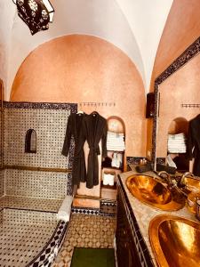 ein Bad mit einem Waschbecken und einem an der Wand hängenden Bademantel in der Unterkunft riad msholidays - privatisé jusqu'à 6 personnes - bassin in Marrakesch