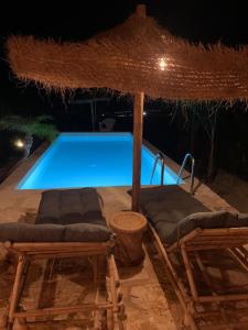a swimming pool with two chairs and an umbrella at Poggio Bellavista in Sampieri