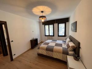 1 dormitorio con cama y lámpara de araña en Residence Valtellina - Salita Baradello en Aprica