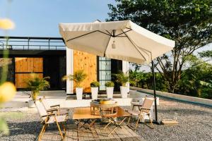 a table and chairs with an umbrella on a patio at Cana​ Garden​ House​ โฮมสเตย์​ in Ban Khok