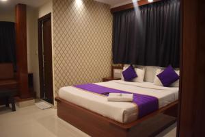 a bedroom with a bed with purple and white pillows at Hotel UR Comforts Jayanagar in Bangalore