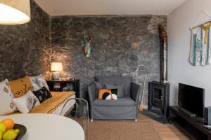 ein Wohnzimmer mit einem Sofa und einem Stuhl in der Unterkunft Casinha dos Canhas by An Island Apart in Ponta do Sol
