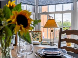 a table with a vase of sunflowers and a lamp on it at Pass the Keys The William Morris Lodge in the centre of Ludlow in Ludlow