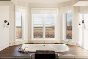een wit bad in een kamer met ramen bij Fox Lane - Prince Edward County Farmhouse in Picton