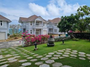 a large white house with a yard with flowers at Villa Sea View Phan Thiet Mui Ne in Mui Ne