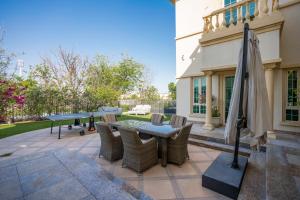 un patio con mesas, sillas y una sombrilla en Jumeirah Islands Private Pool Villa, en Dubái