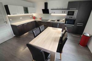 uma cozinha com uma mesa de madeira e cadeiras pretas em Apartmán u Trojmezí em Pŭlgrun