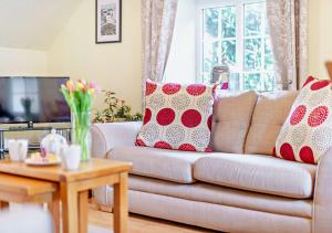 a living room with a couch with red and white pillows at Wren Cottage - Bedale in Hornby