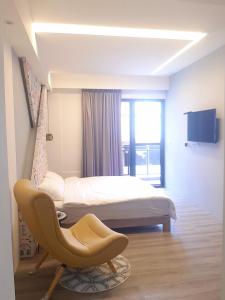 - une chambre avec un lit, une chaise et une télévision dans l'établissement 台東有點田民宿, à Guanshan