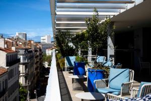 einen Balkon mit blauen Stühlen und Tischen auf einem Gebäude in der Unterkunft OKKO Hotels Toulon Centre in Toulon