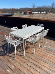 une table blanche et quatre chaises sur une terrasse dans l'établissement Hygge House Cozy Boutique Guest House, à Hillier