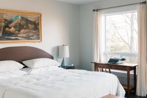 a bedroom with a bed and a desk and a window at Tanglewood - Large Waterfront Home in PEC ST-2020-0172 in Waupoos