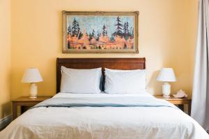 a bedroom with a bed with two lamps and a painting at Tanglewood - Large Waterfront Home in PEC ST-2020-0172 in Waupoos