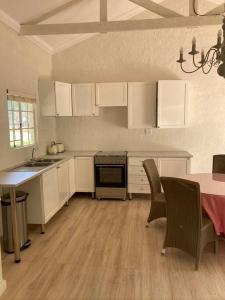 a kitchen with white cabinets and a table with chairs at Dainty Bess cottage in Middelburg