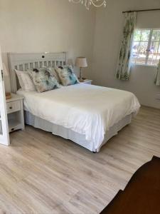 a bedroom with a white bed and a wooden floor at Dainty Bess cottage in Middelburg