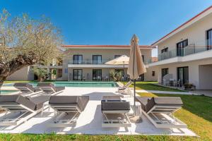 a group of lounge chairs and an umbrella next to a pool at AlexMare Hotel Fourka in Skala Fourkas
