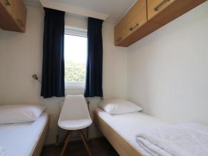 twee bedden in een kamer met een raam en een stoel bij Modern chalet in Grou with a spacious garden in a beautiful location in Grou