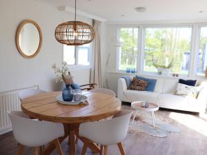 een woonkamer met een houten tafel en witte stoelen bij Modern chalet in Grou with a spacious garden in a beautiful location in Grou
