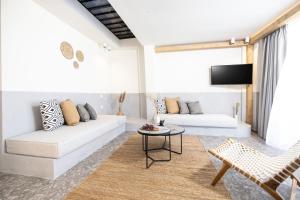 sala de estar con 2 sofás blancos y TV en Kaktus Suites Private Pool, en Paliouri
