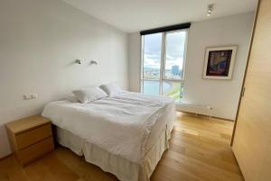 een witte slaapkamer met een bed en een groot raam bij Luxury apartment downtown Reykjavik with stunning views in Reykjavík