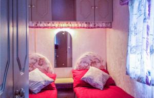 a bedroom with two beds with red sheets and a mirror at Nice Caravan In Smoldzino With 2 Bedrooms in Gardna Wielka