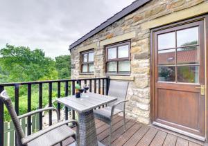 a patio with a table and chairs on a balcony at Woodpecker Cottage in Hutton le Hole