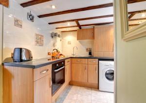 a kitchen with wooden cabinets and a washer and dryer at Woodpecker Cottage in Hutton le Hole