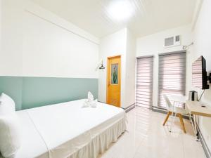 ein weißes Schlafzimmer mit Bett und Schreibtisch in der Unterkunft Verra Inn in Tagaytay