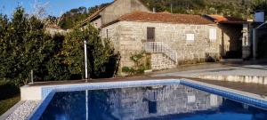 a swimming pool in front of a stone house at Recanto da Costa in Riba de Mouro