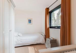 biała sypialnia z łóżkiem i oknem w obiekcie Wildewood Cottage w mieście Robin Hood's Bay