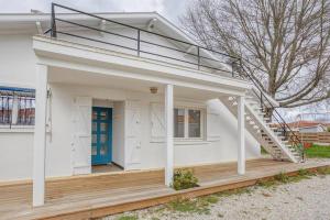 a white house with a porch and a blue door at Maison de vacances Bisca in Biscarrosse