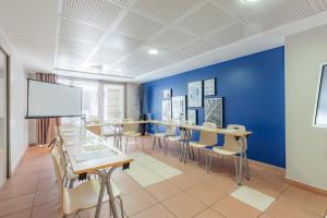 une salle de classe avec des tables et des chaises et un mur bleu dans l'établissement Appart'City Confort La Ciotat - Côté Port, à La Ciotat
