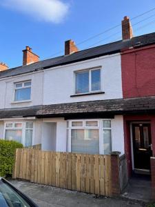 a white and red house with a wooden fence at It's Broadway Baby! Great house close to City Centre in Belfast