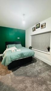 a bedroom with a bed with a green wall at UR PLACE in Manchester