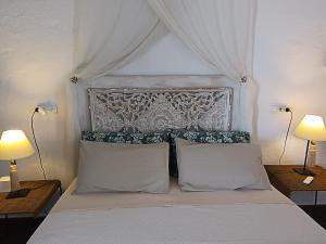 a bedroom with a white bed with two lamps at wonderful sunsets views from terraces Last minute in Cala Vadella